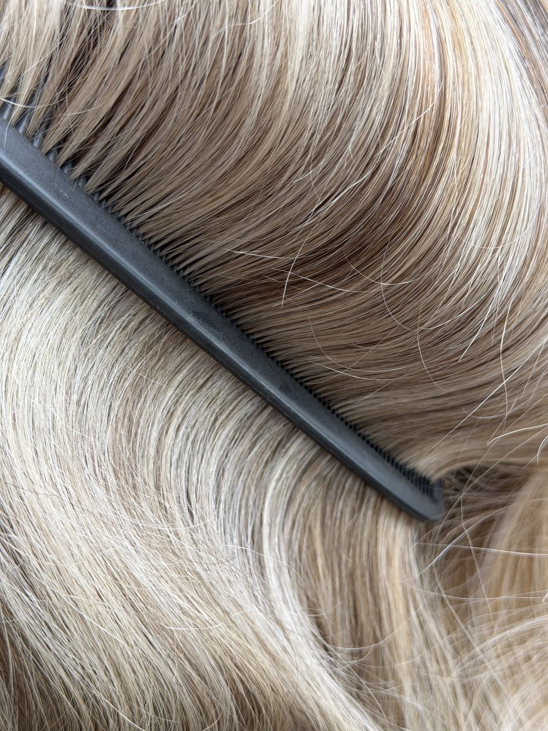 Nahaufnahme von blondiertem Haar mit Balayage beim Kämmen